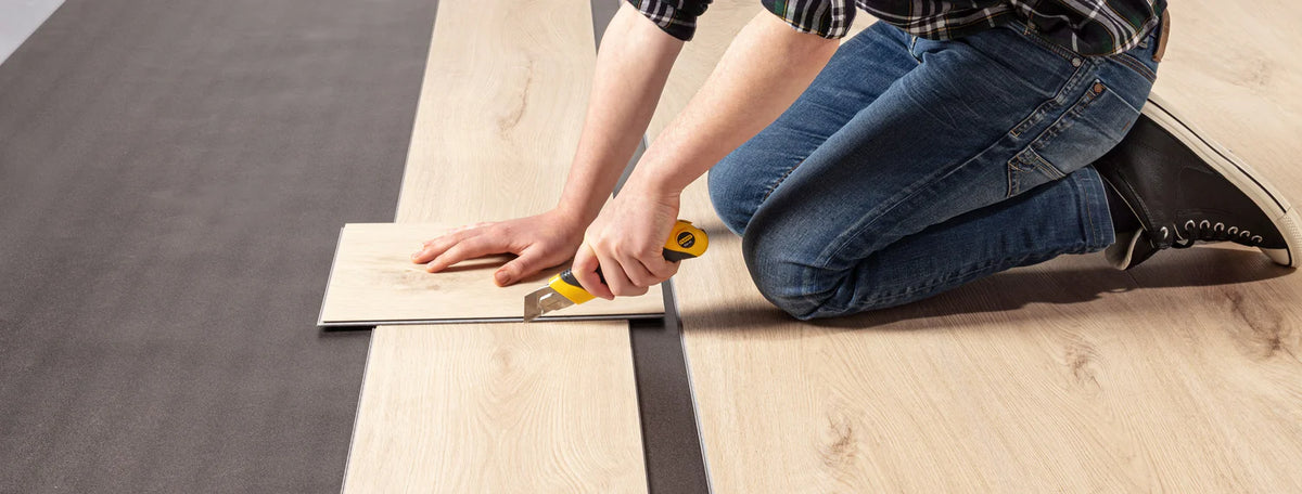 Een legger legt een PVC-vloer in een woonkamer